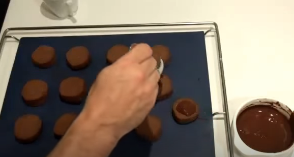 Colocando una cucharada de chocolate sobre cada polvorón